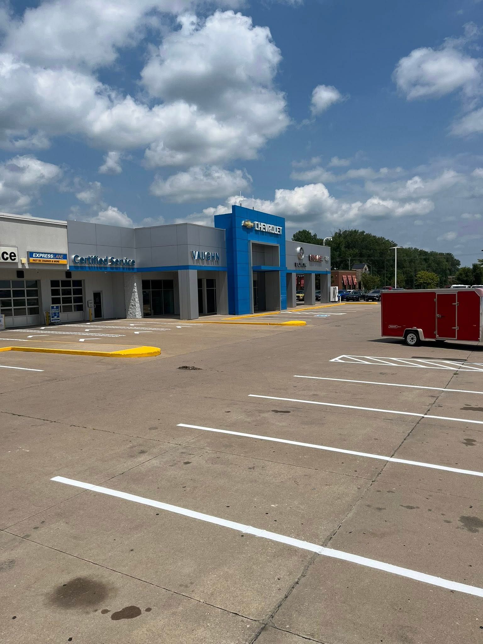 Empty parking lot in front of a store with a blue entrance under a cloudy sky
