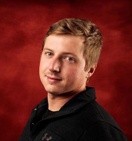 Portrait of a young man in a black shirt against a red studio background