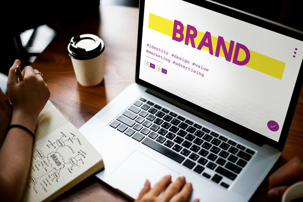 A person is using a laptop computer with the word brand on the screen.