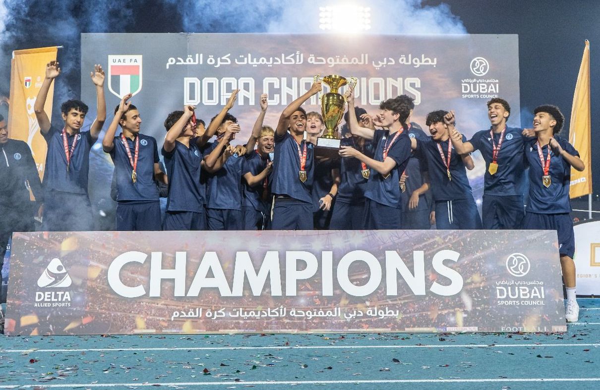 A group of young boys are posing for a picture holding a trophy