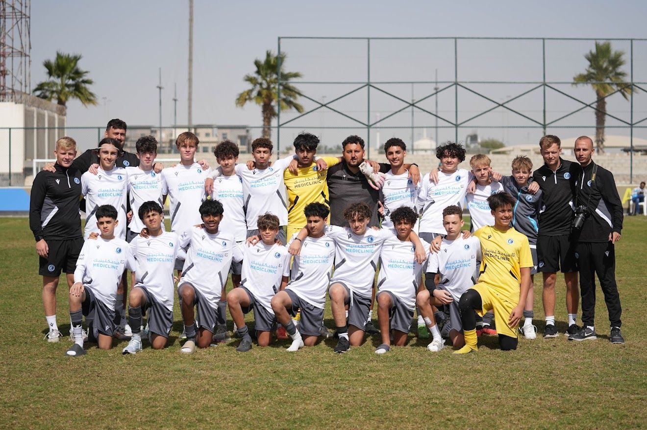 A group of young girls are posing for a picture on a soccer field.