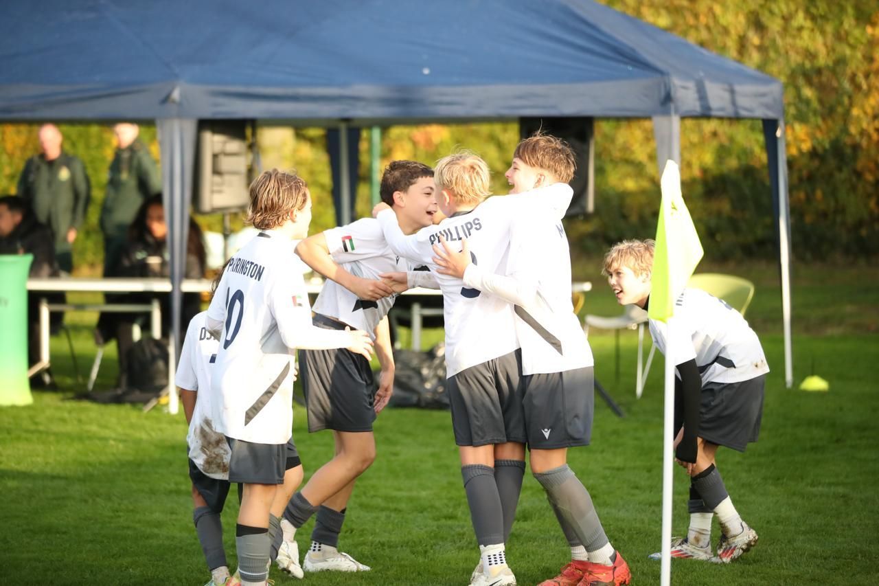 Two young men are hugging each other on a soccer field.