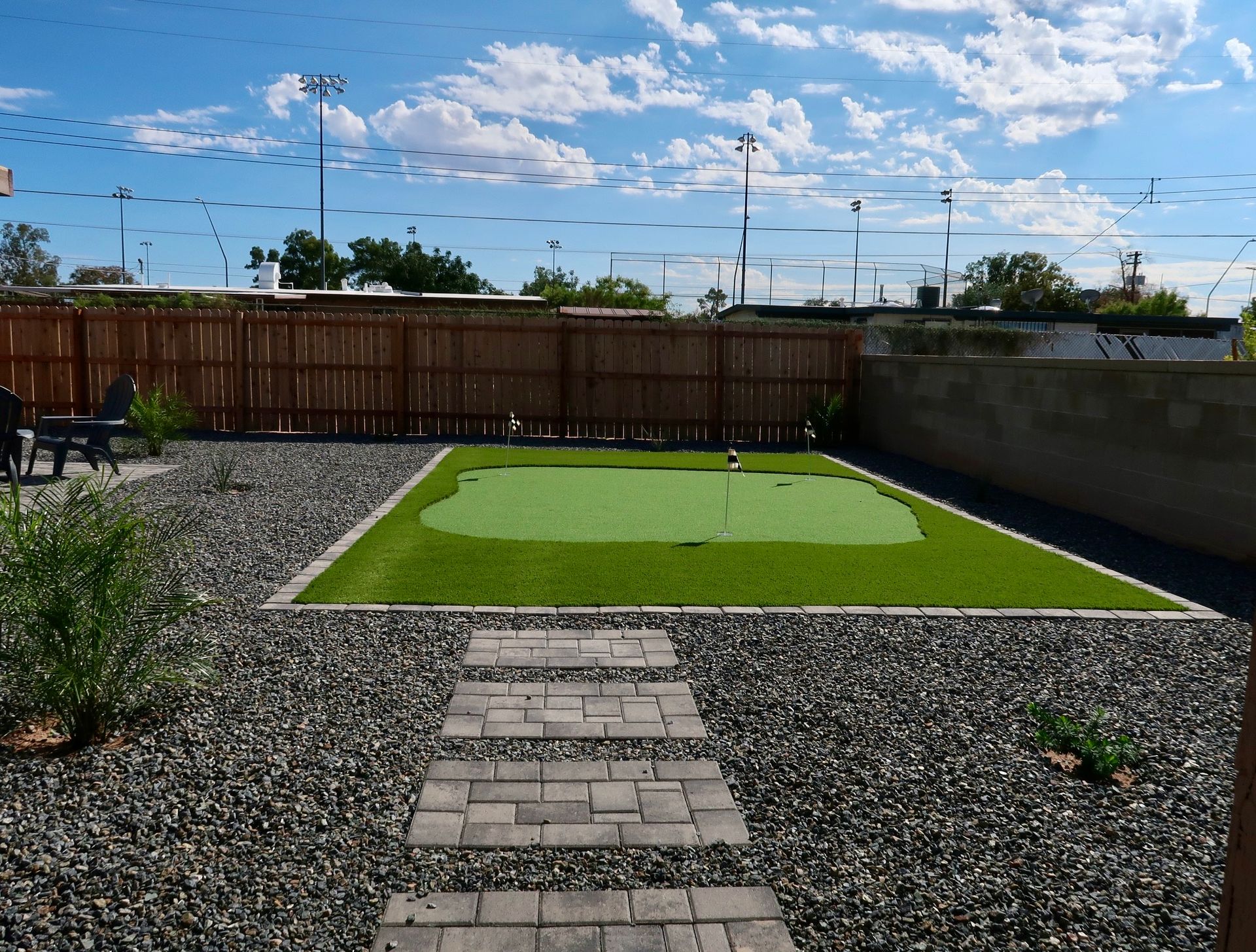 A mini golf course in the backyard with paver walkway.