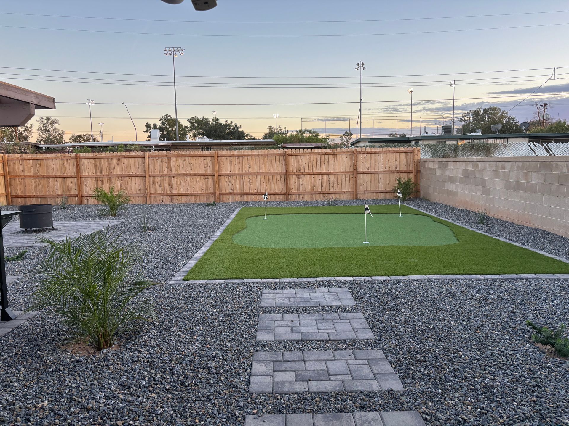 A mini golf course in the backyard with paver walkway.