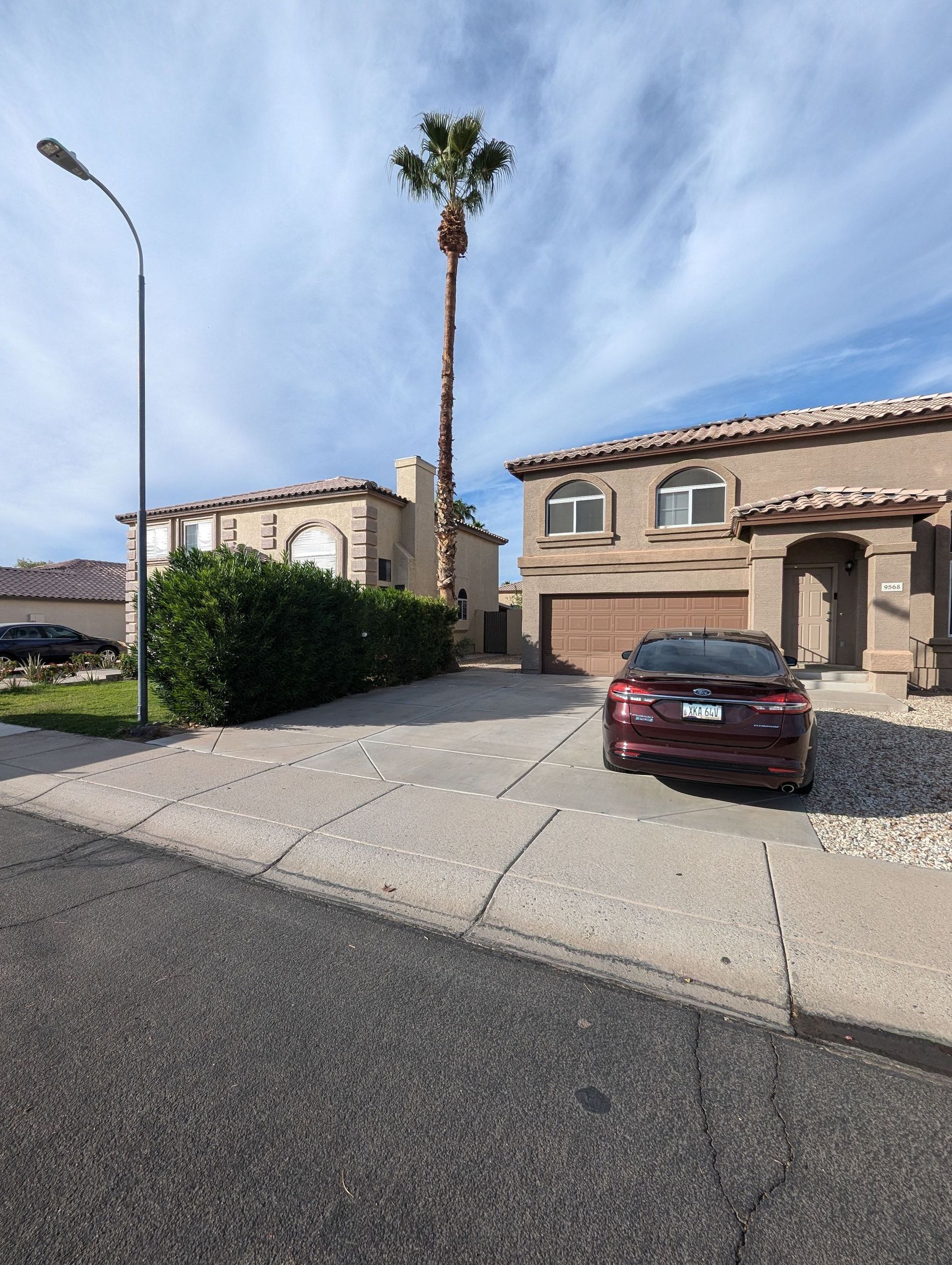 A red car is parked in front of a large house
