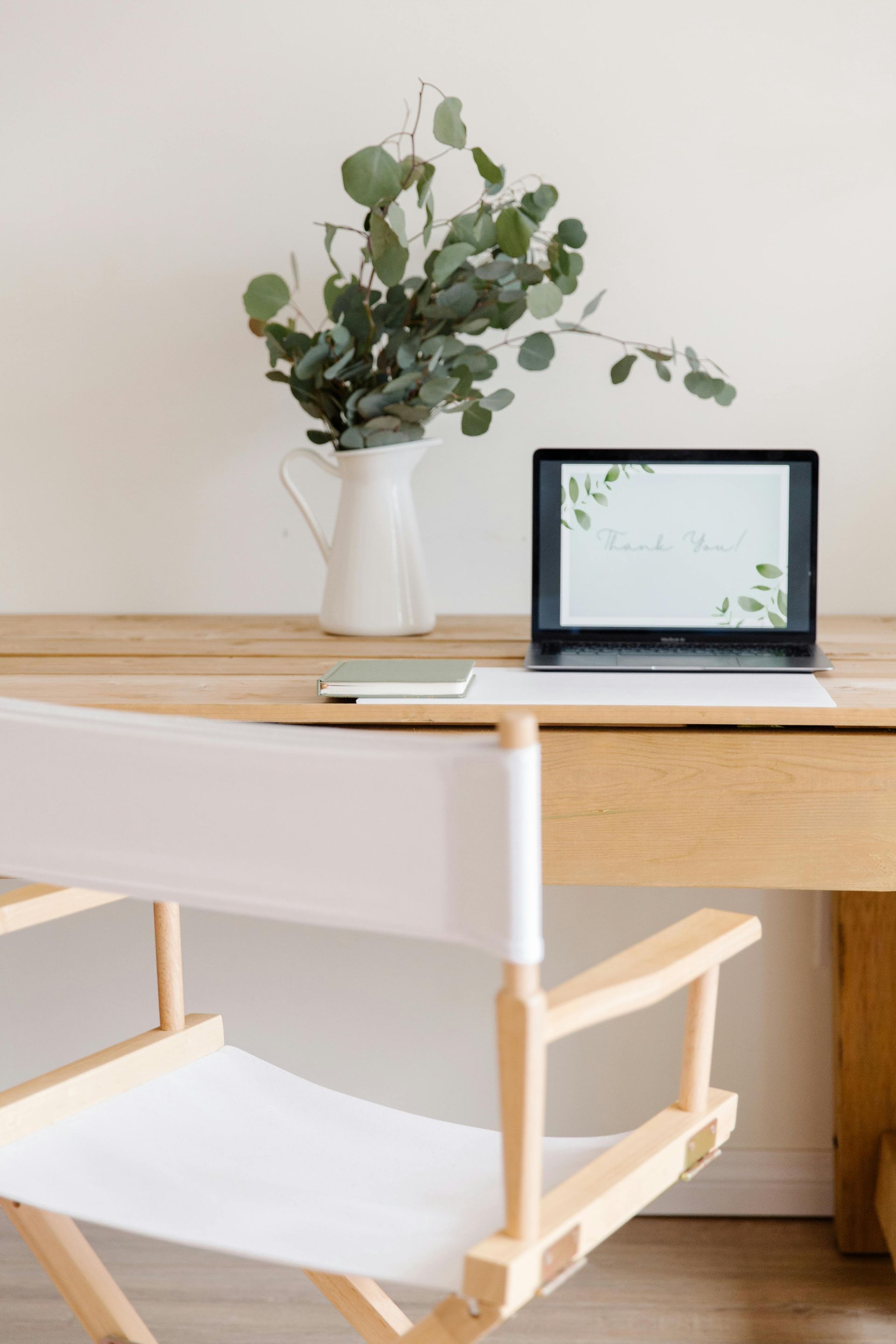 Bureau met laptop en groen, witte stoel in lichte kamer.