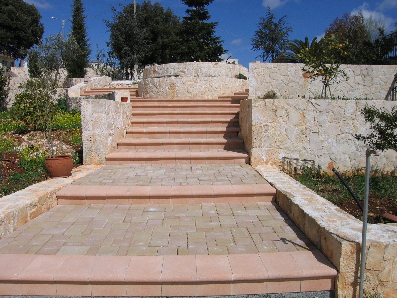 Scala in pietra che conduce a un giardino a più livelli. Gradini e muri marroni.