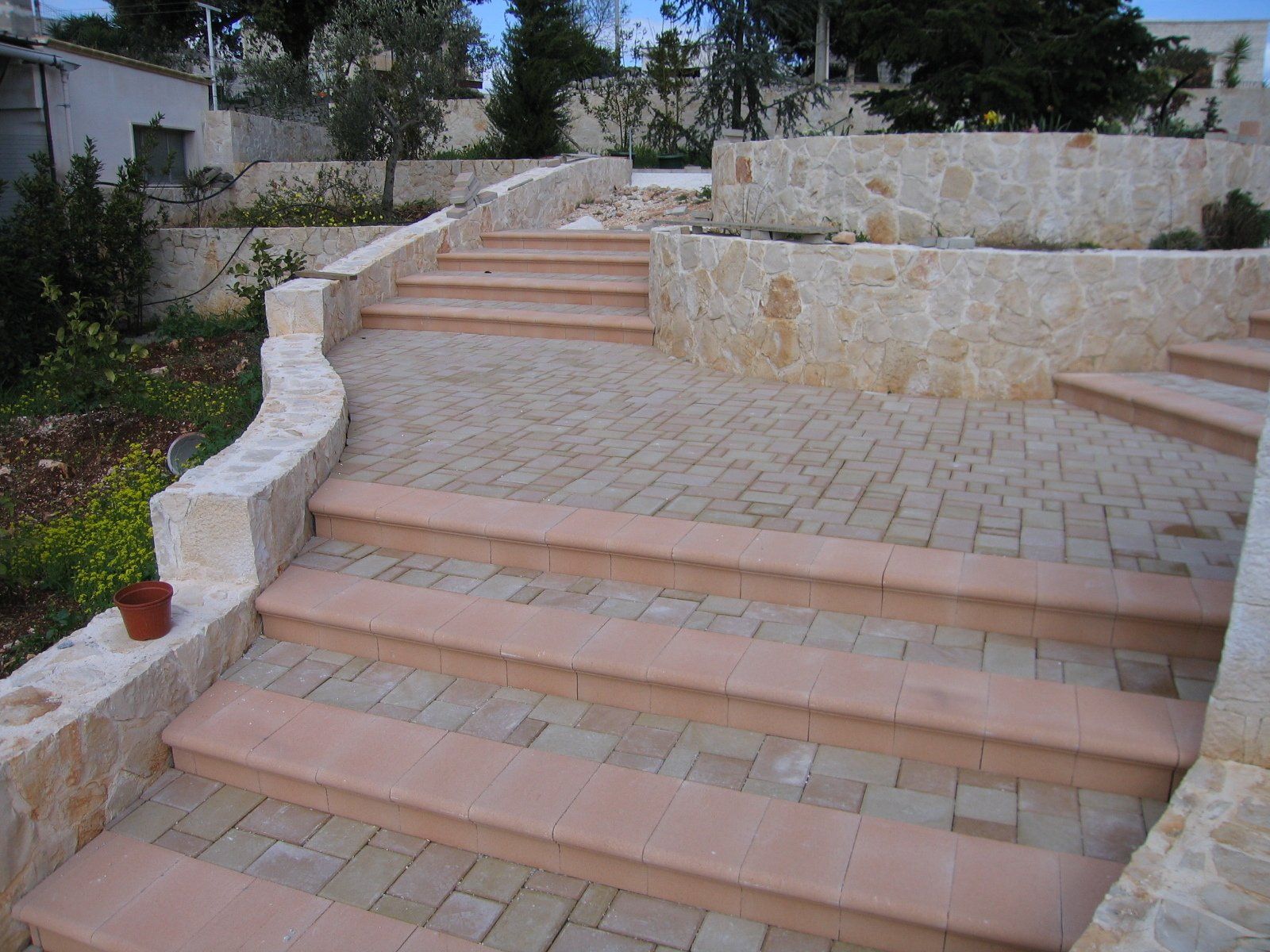 Gradini in pietra e passerella pavimentata in un giardino terrazzato.