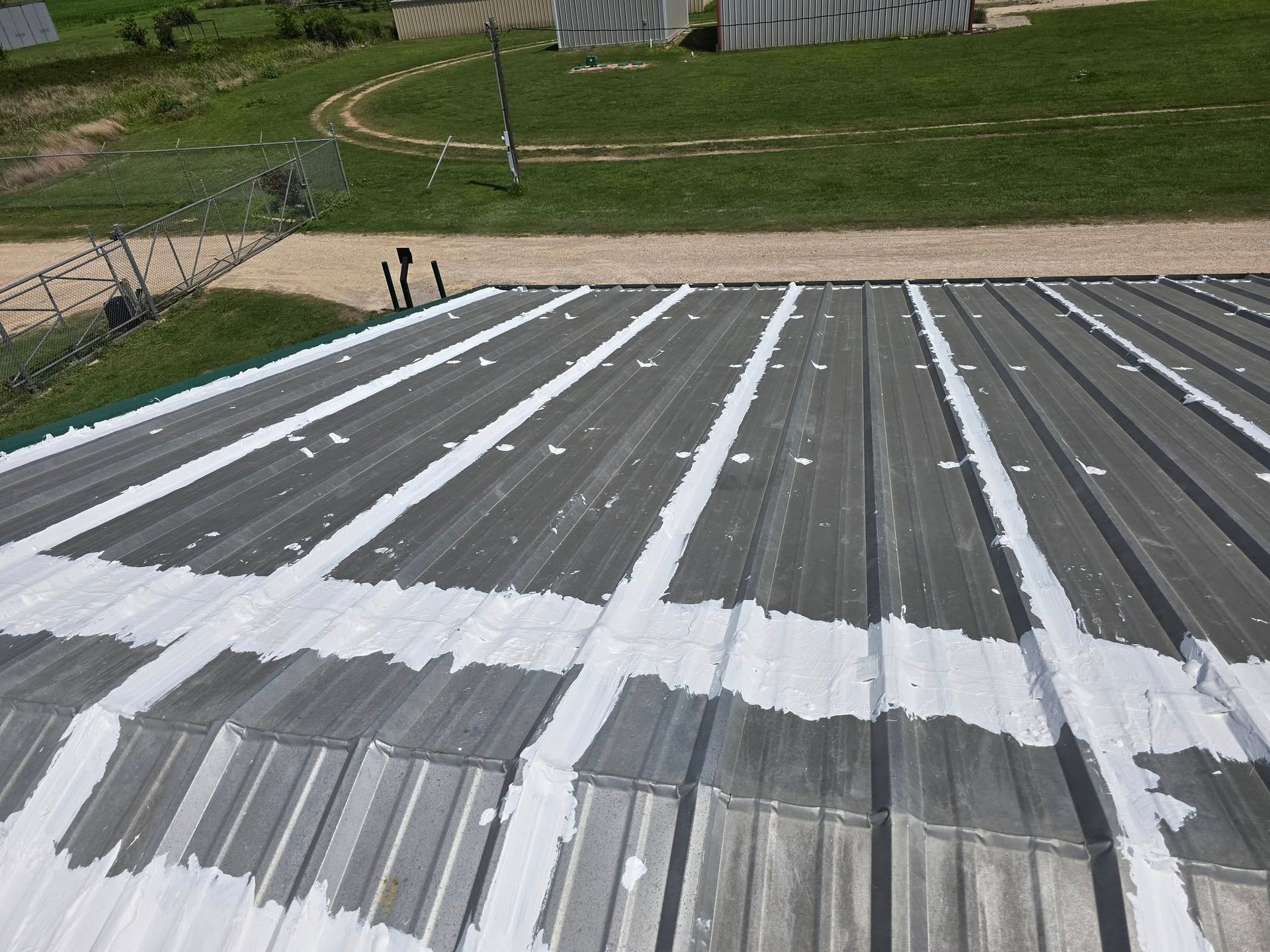 Rooftop with gray metal panels and white snow patches, viewed from above