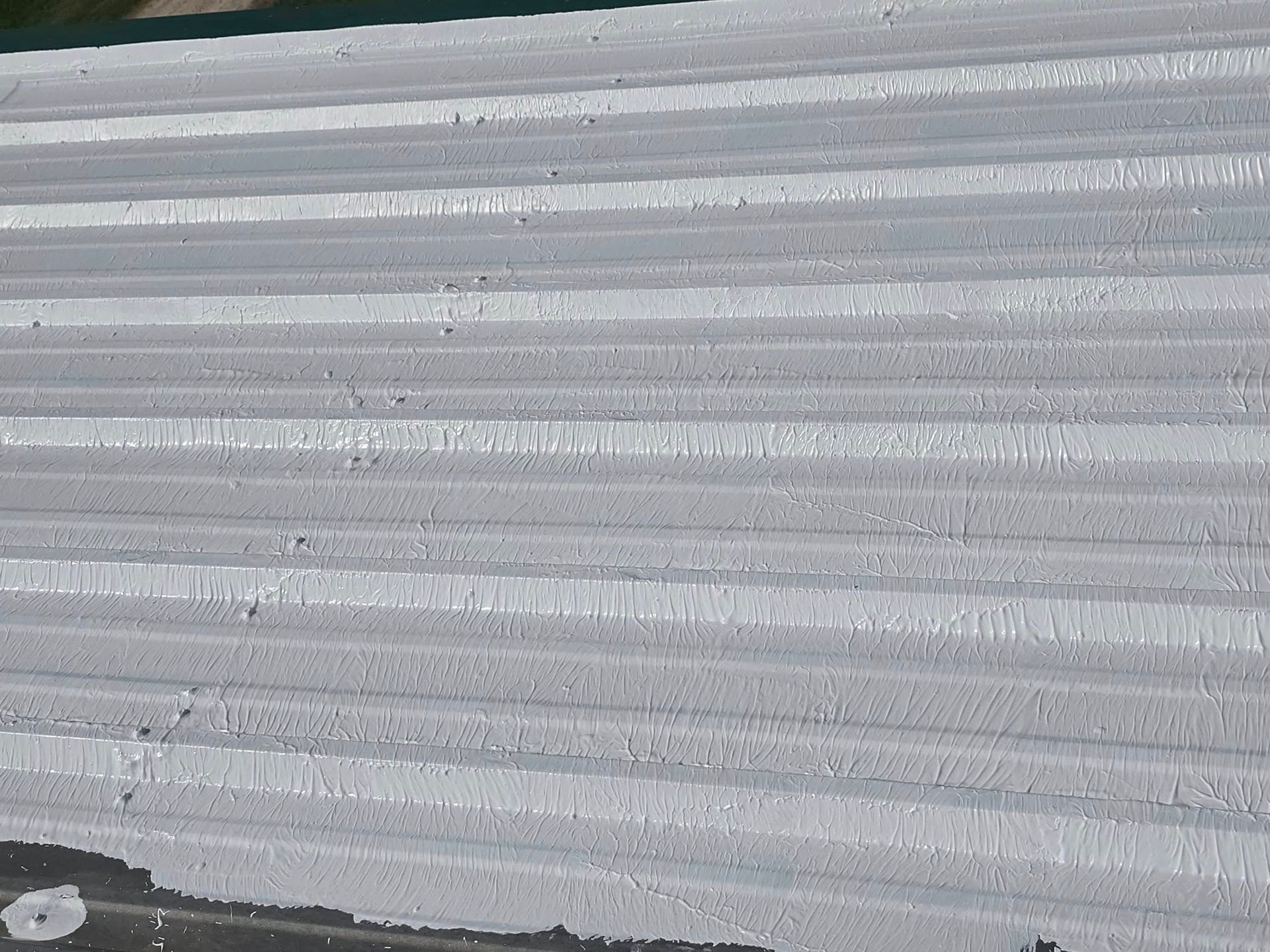 Close-up of a gray corrugated metal surface with a small dark area at the bottom left.
