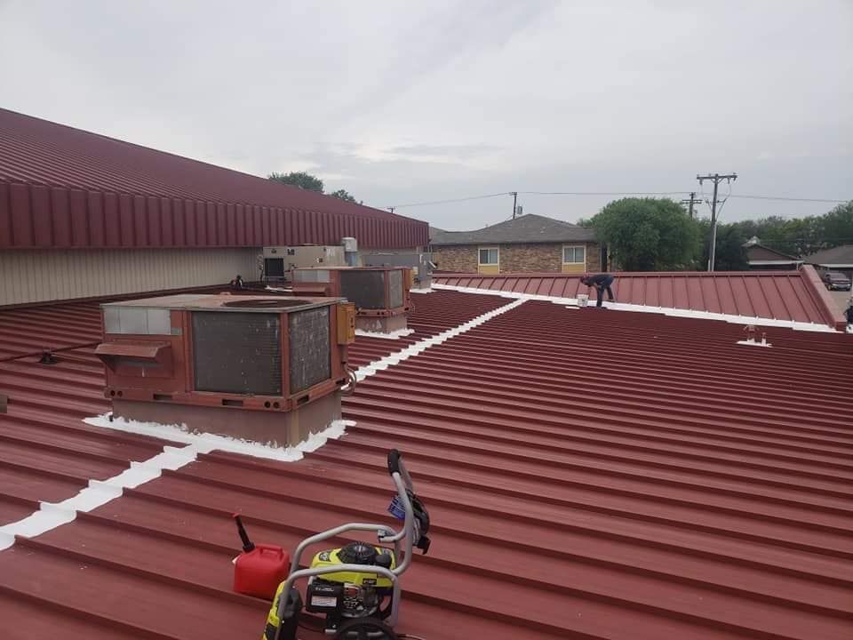 Rooftop with red metal panels, HVAC unit, and rooftop work gear under cloudy sky