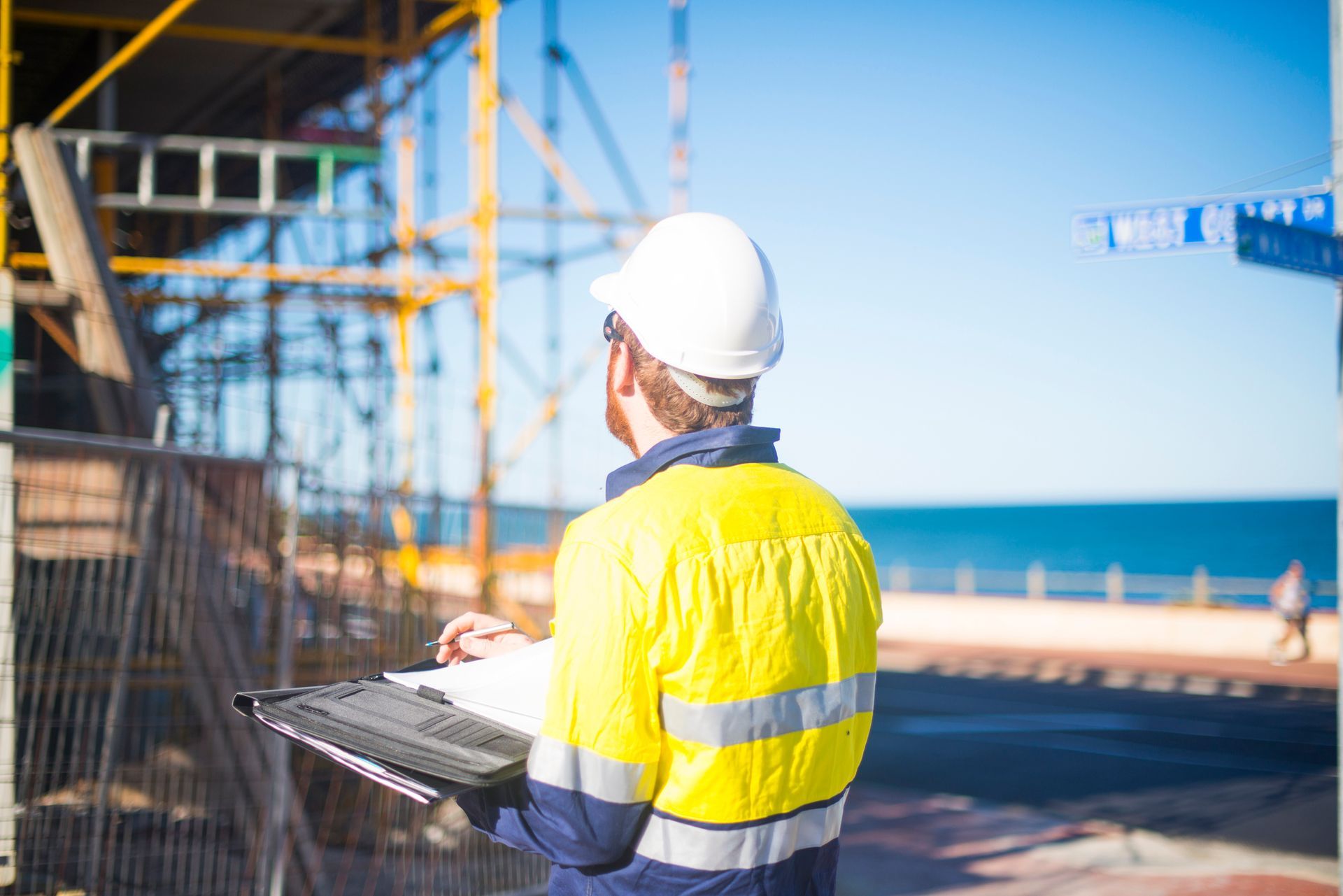 A construction worker is looking at a clipboard at a construction site.
