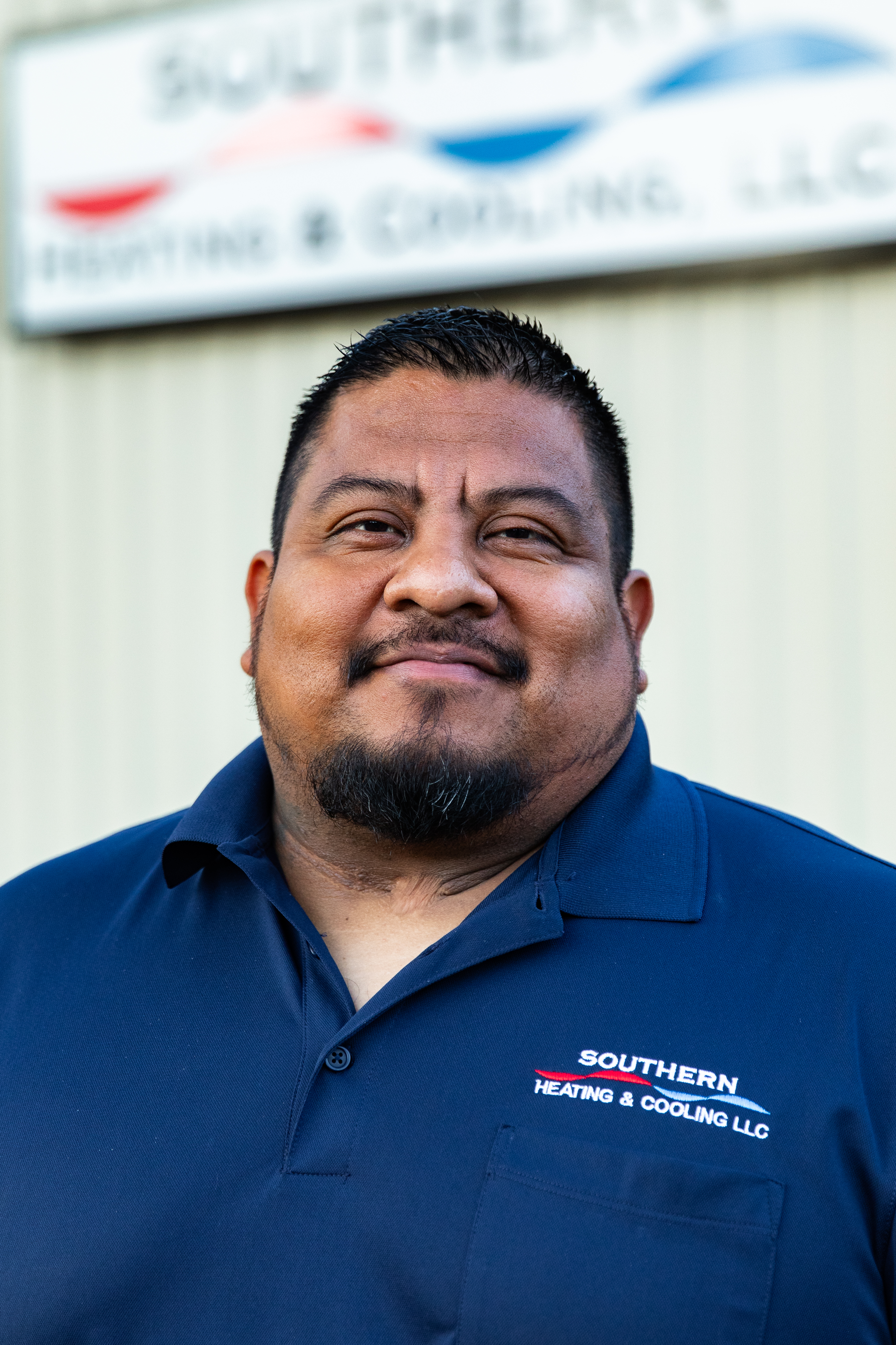 Three people sitting outdoors. Man with a beard, woman with glasses, and a person with short dark hair.