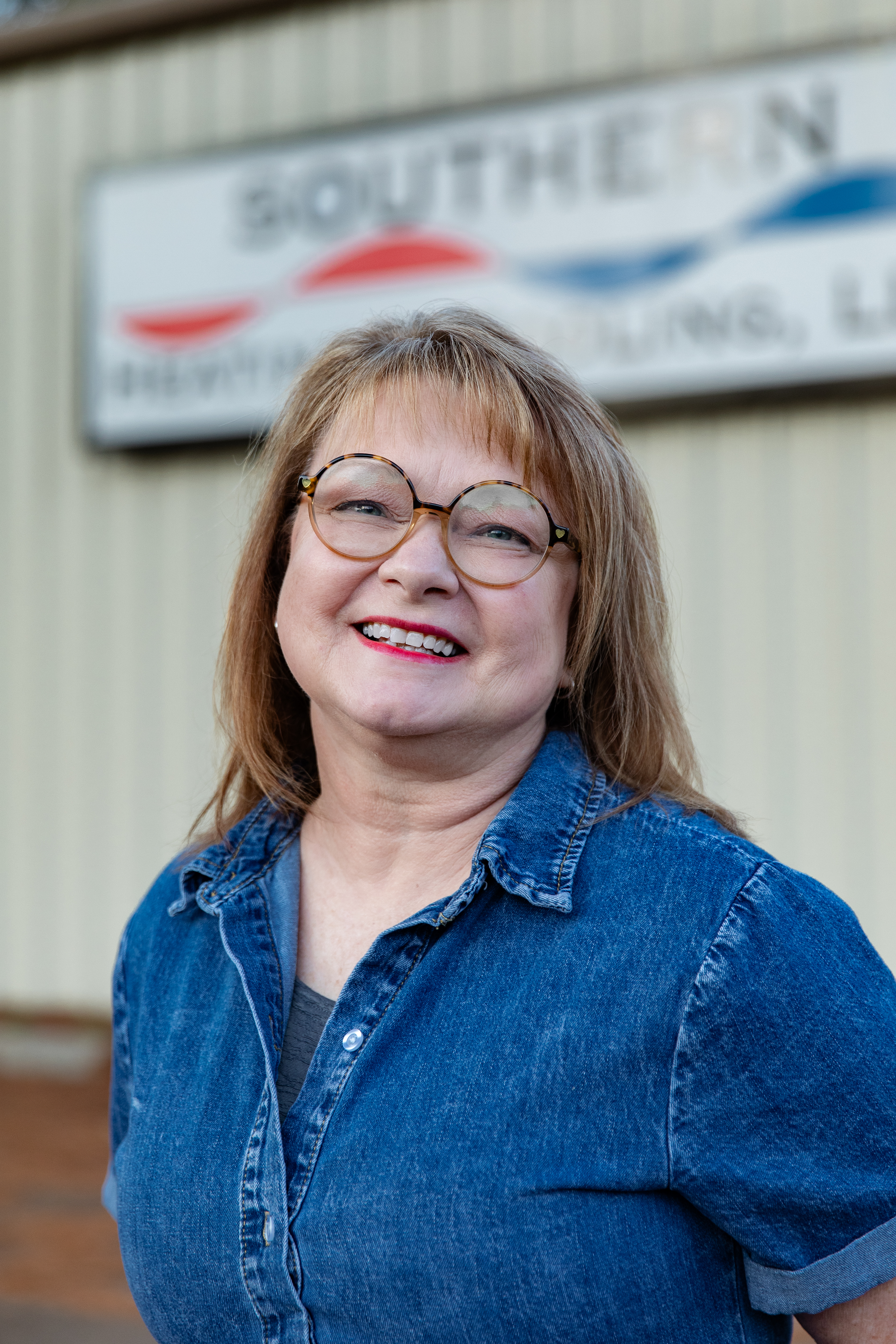 Family of nine poses outdoors, smiling. Includes adults and children, autumn setting, trees and foliage.