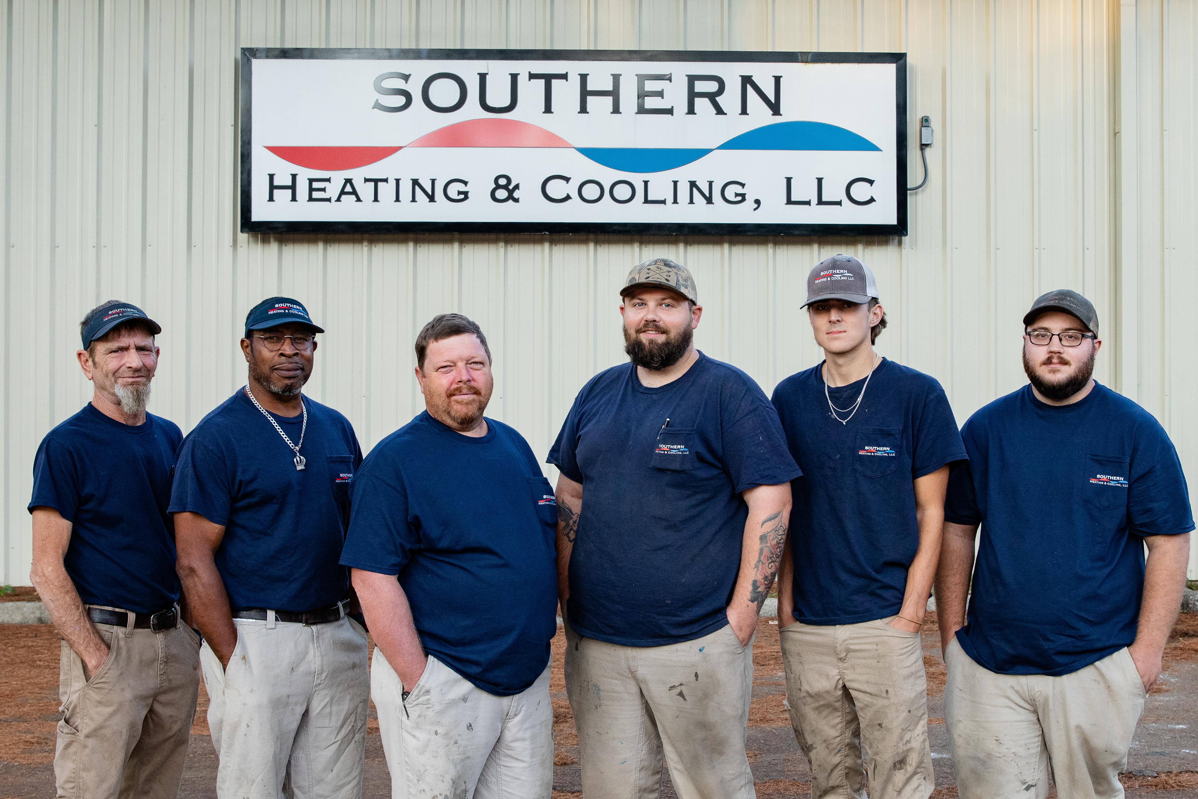 Five men in matching uniforms stand outside a building with 