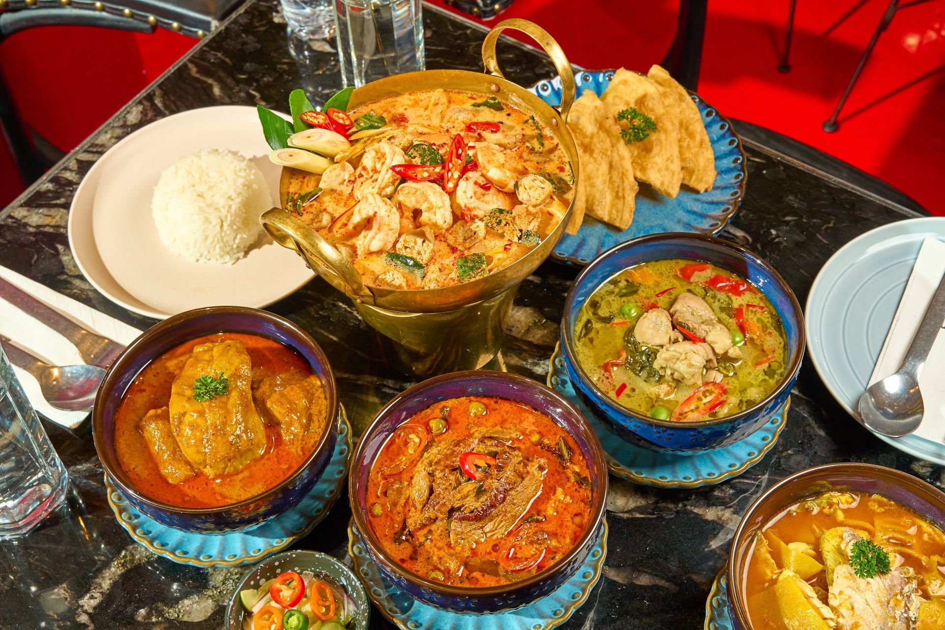 Caribbean dishes including oxtail, jerk chicken, and roti on a warm wooden surface