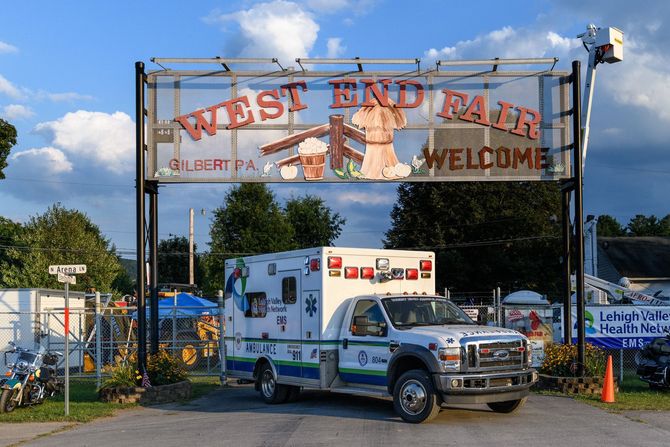 An ambulance is parked in front of a sign that says west end fair welcome