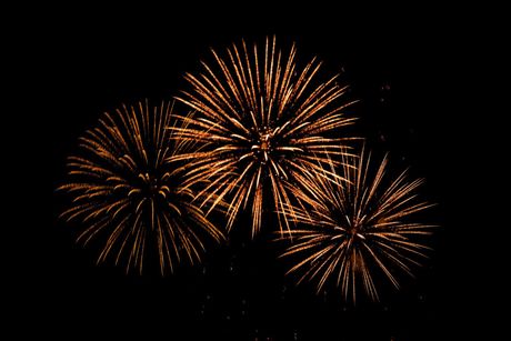 Three fireworks are exploding in the night sky