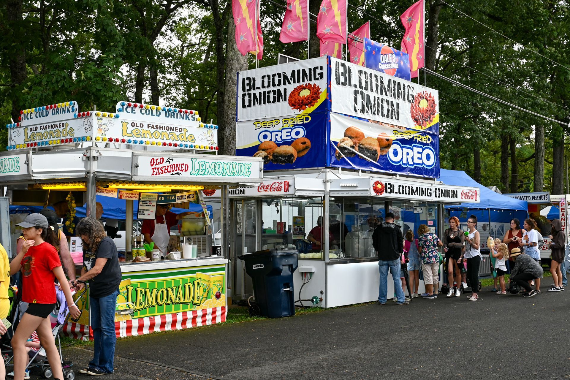 A group of people standing in front of a food stand that says oreo