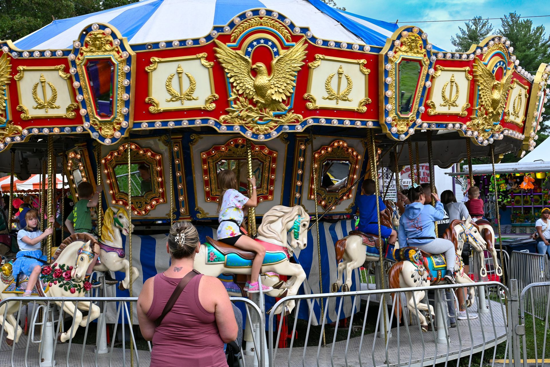 A woman is taking a picture of a merry go round at an amusement park.