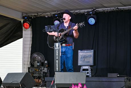 A man is playing a guitar and singing into a microphone on a stage.
