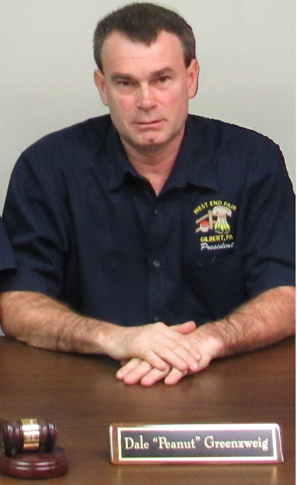 A man in a blue shirt sits at a desk with a name plate that says dale peanut groenaweig