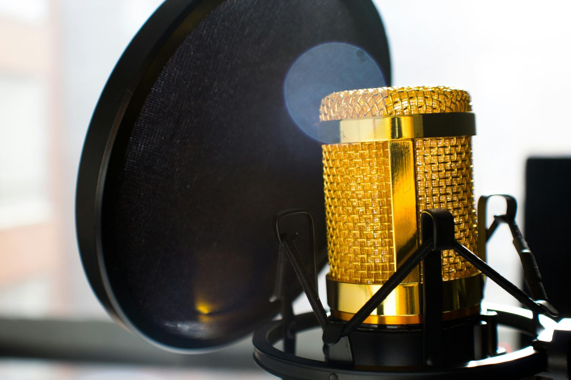 Gold microphone with pop filter in a recording studio setup