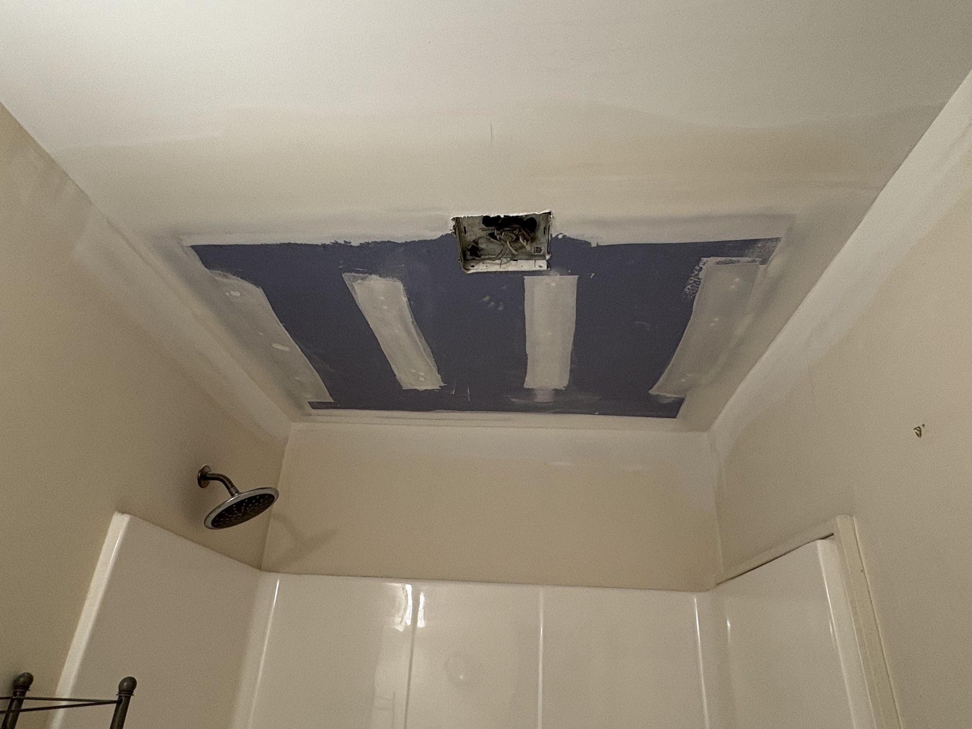 A bathroom with a shower and a ceiling that is being painted.