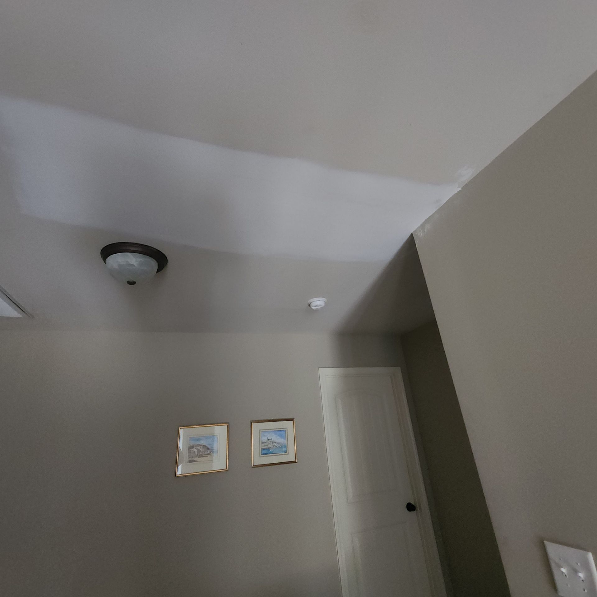 A hallway with two pictures on the wall and a light on the ceiling