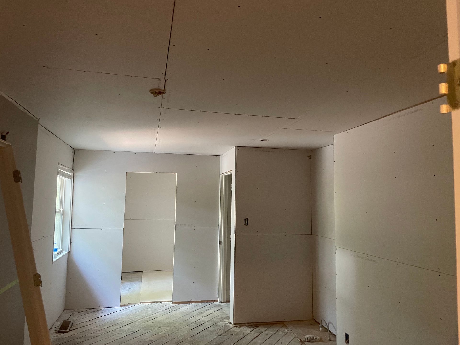 A room that is being remodeled with drywall on the walls and ceiling.