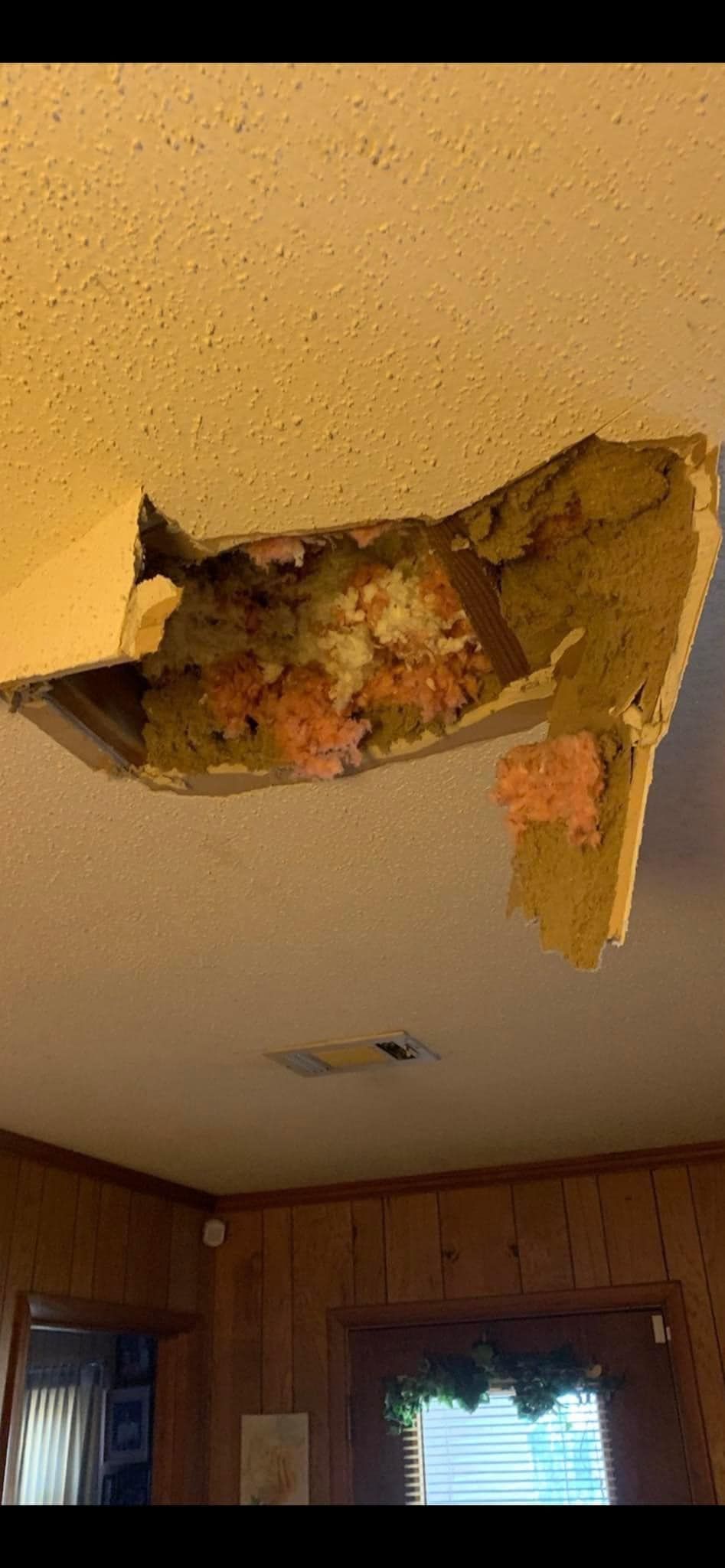 A piece of insulation is hanging from the ceiling of a room.