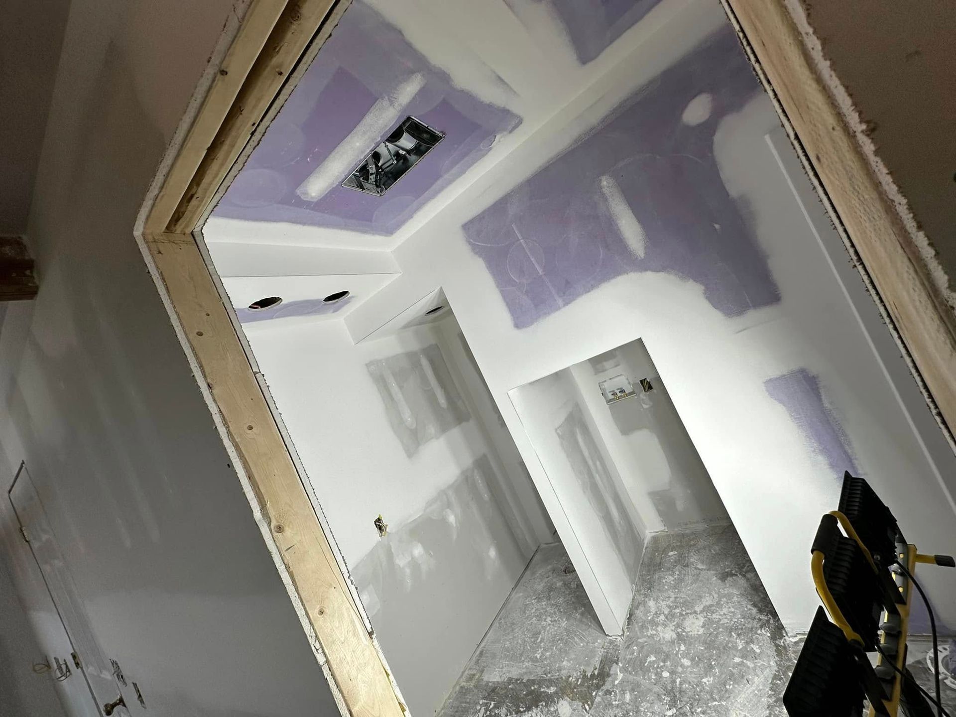 A room that is being remodeled with drywall on the walls and ceiling.