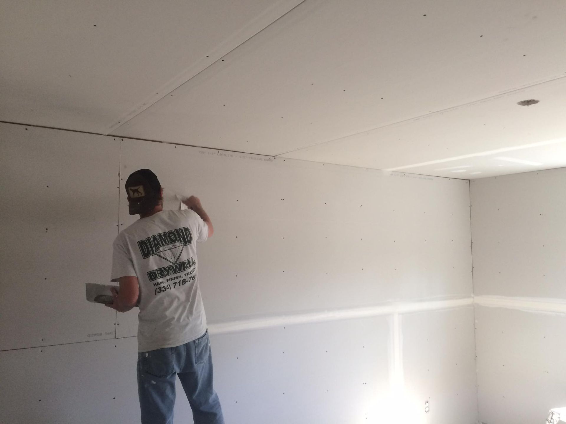 A man is standing in a room with a white wall.