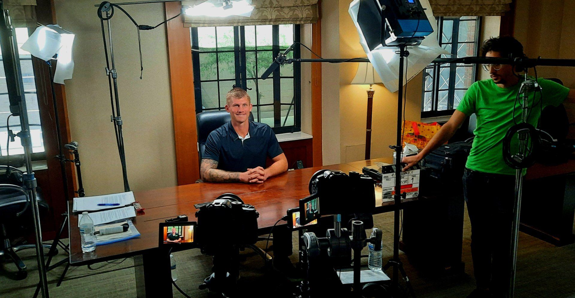 A man sitting with camera equipment around him for an interview