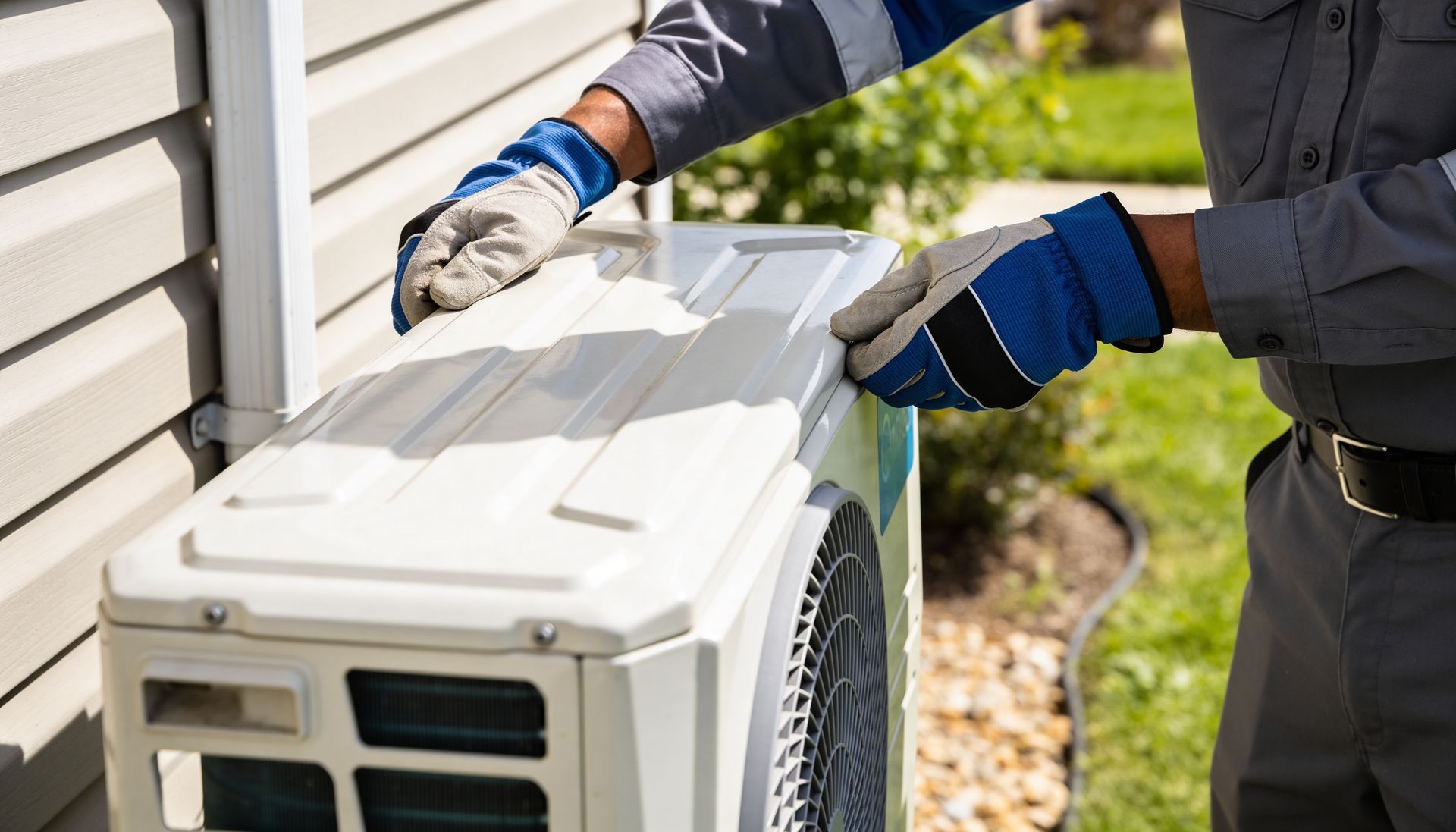 HVAC technician in gloves removing the cover panel of an outdoor air conditioning unit for diagnosti