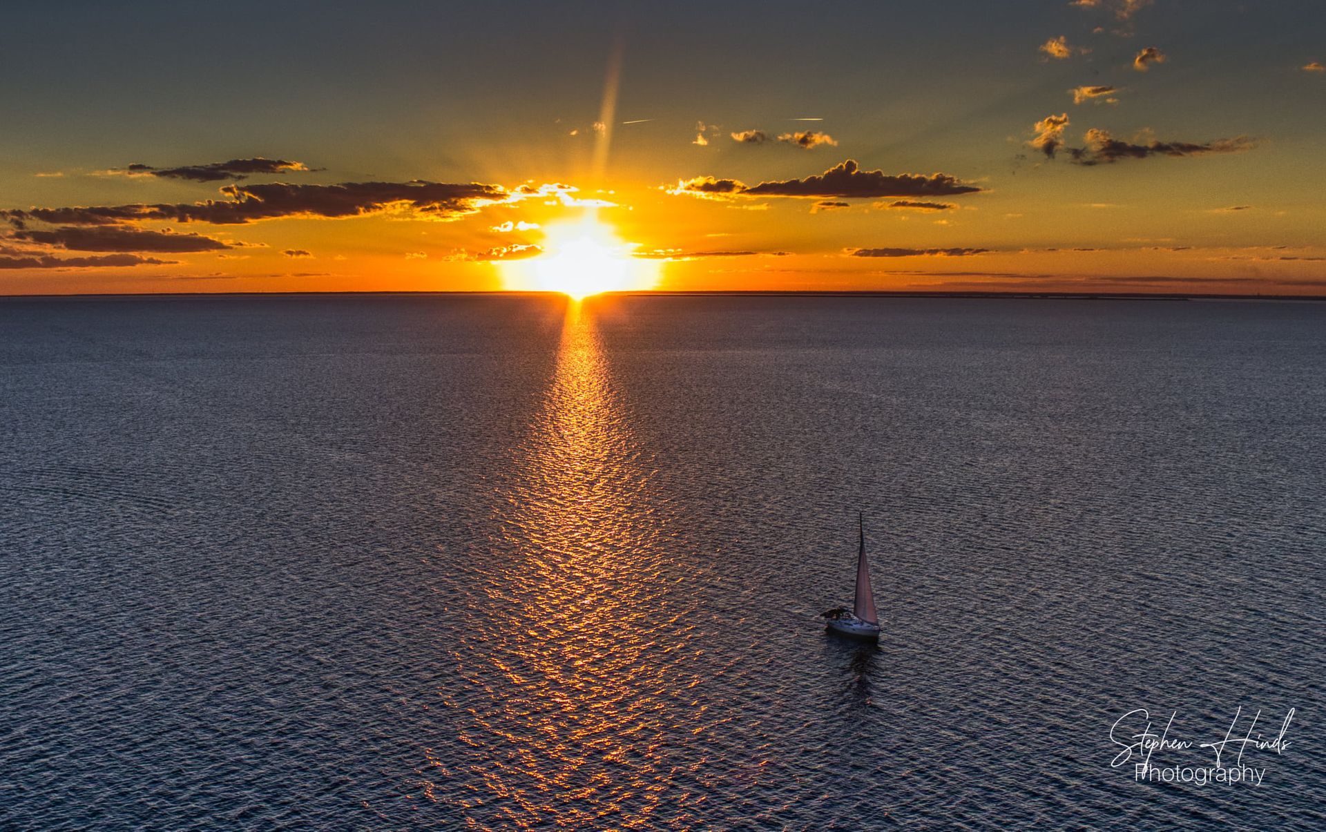 An aerial view of a sailboat in the ocean at sunset by stephen hill photography