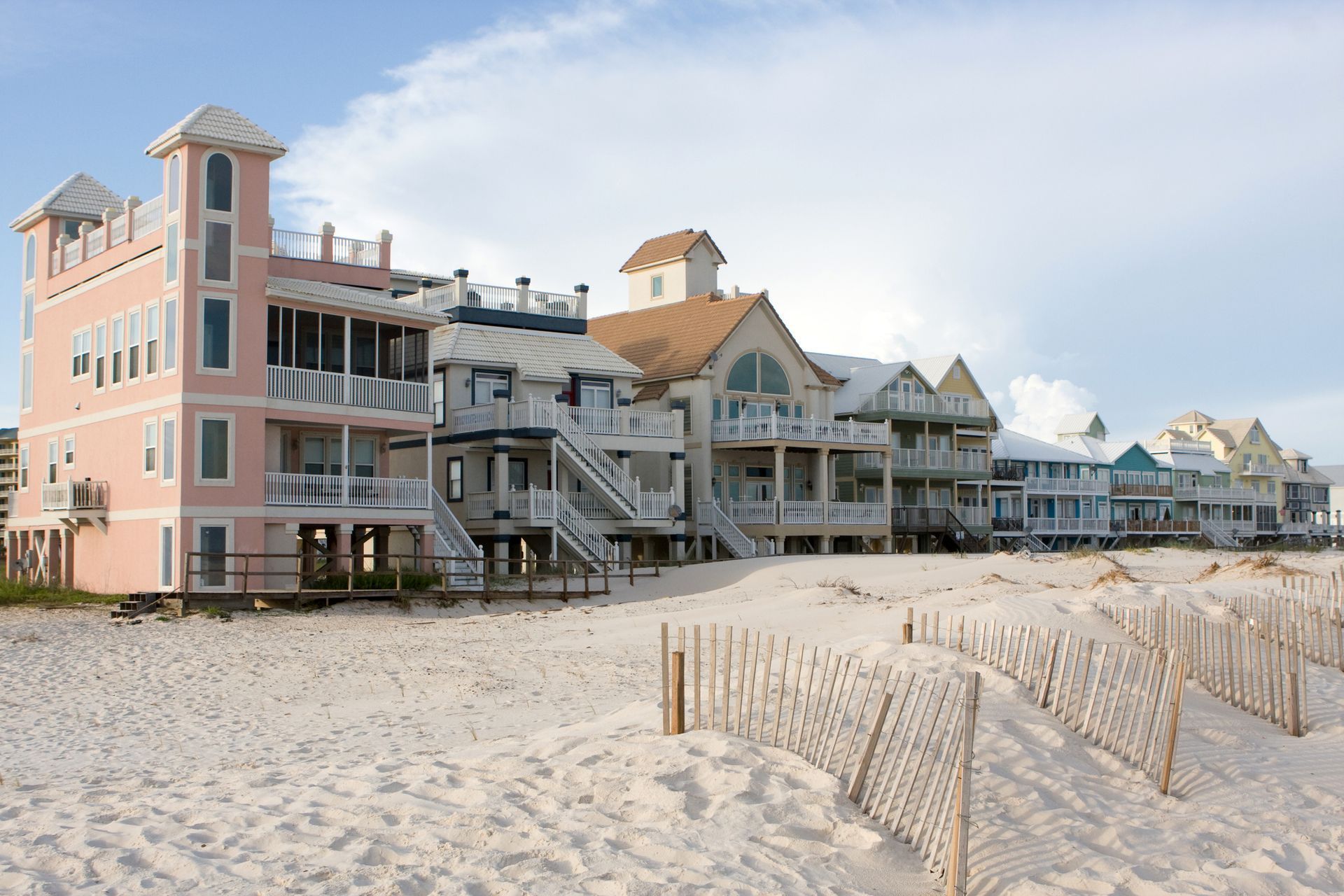 A row of beach houses are lined up on a sandy beach