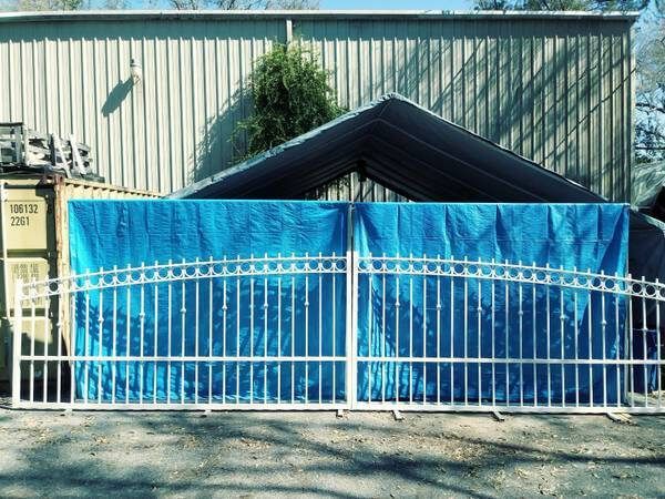 A blue tarp is covering a metal gate in front of a building