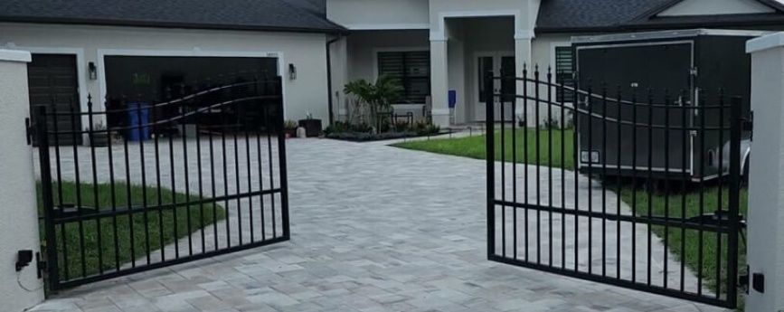 A black gate is open in front of a white house.