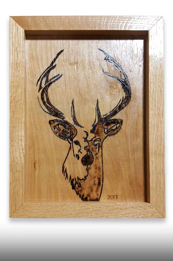 Wooden plaque with a carved deer head and antlers on a light wood background