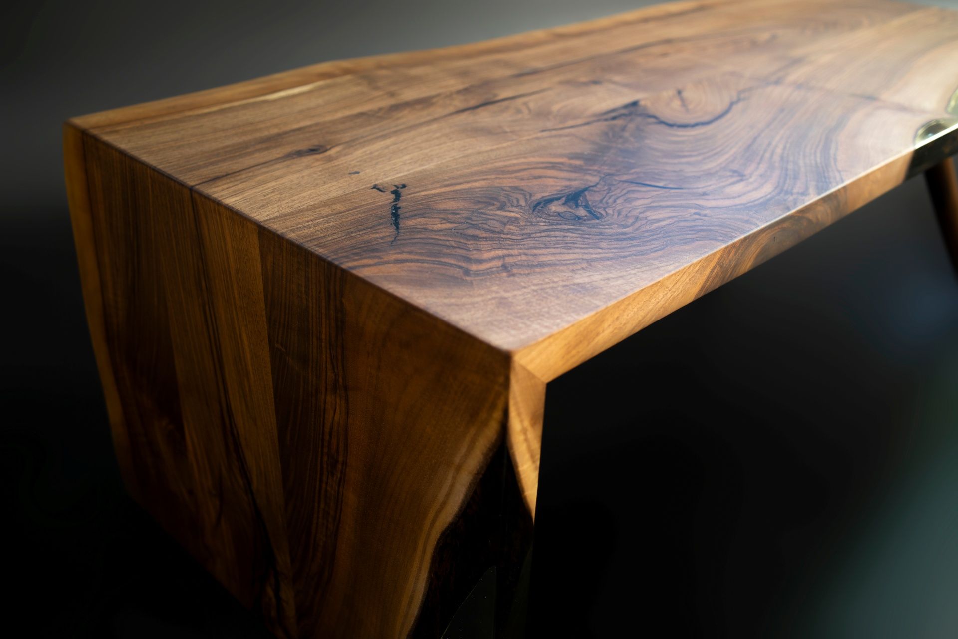 Close-up of a polished wooden table edge with a live edge and dark grain pattern