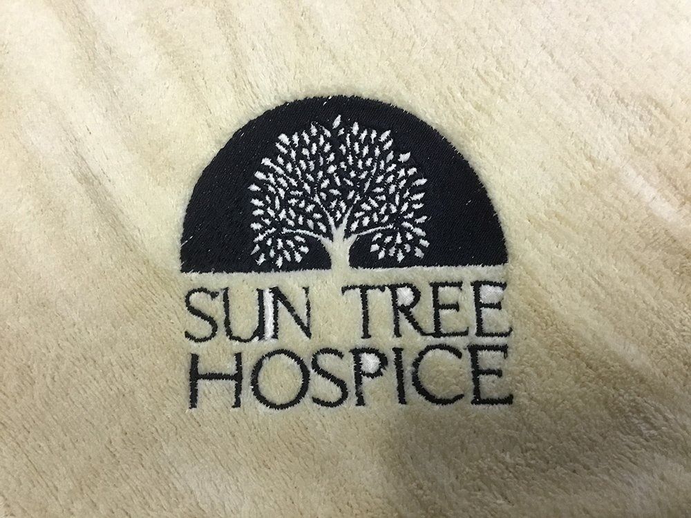 Logo for Sun Tree Hospice featuring a black semi-circle with a white tree inside, above the text