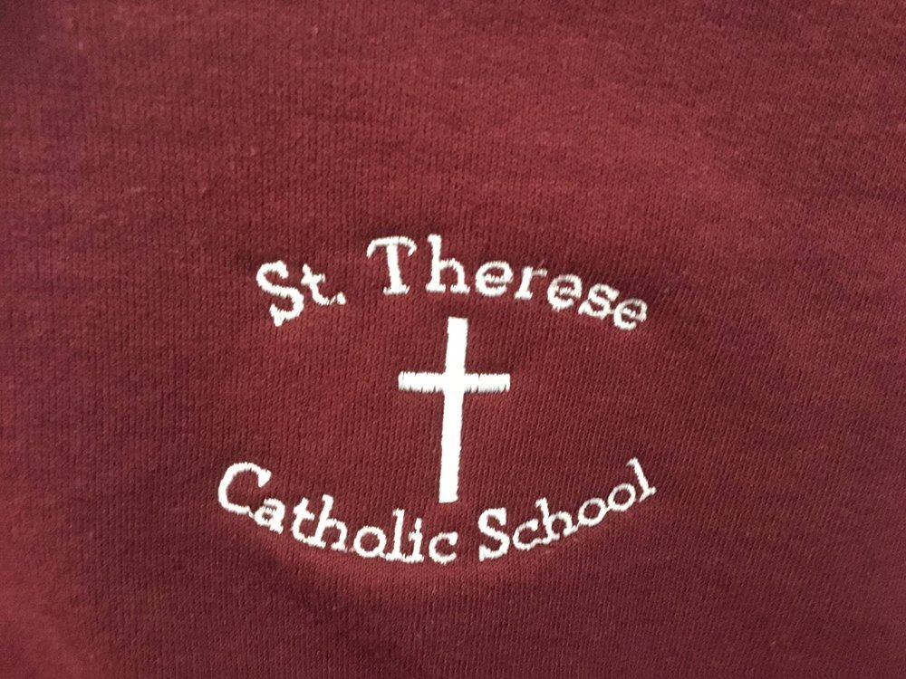 White embroidery on a dark red fabric reads
