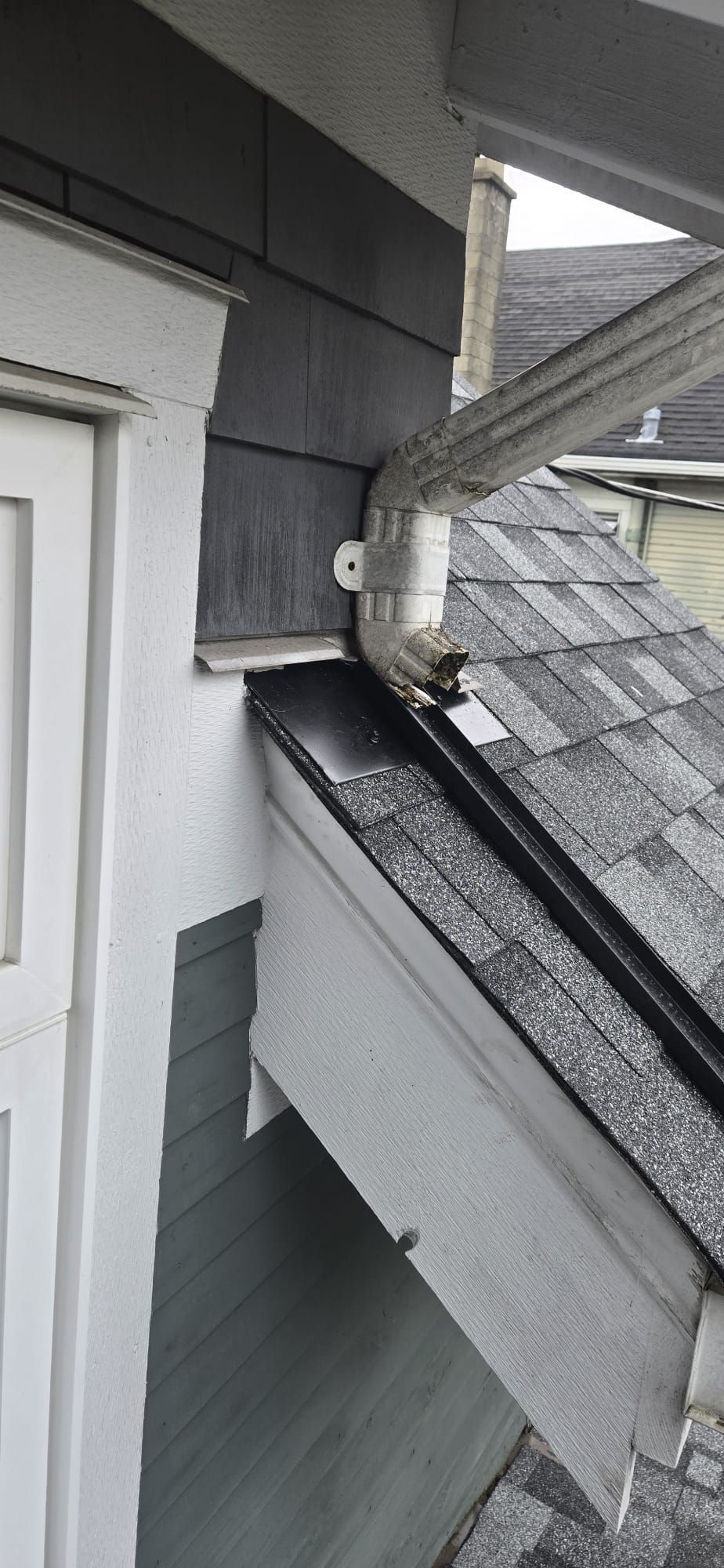 Black wall flashing under cedar shingle siding with custom bent water channel carrying downspout water onto lower roof plane, Vancouver, Paragon Roofing BC