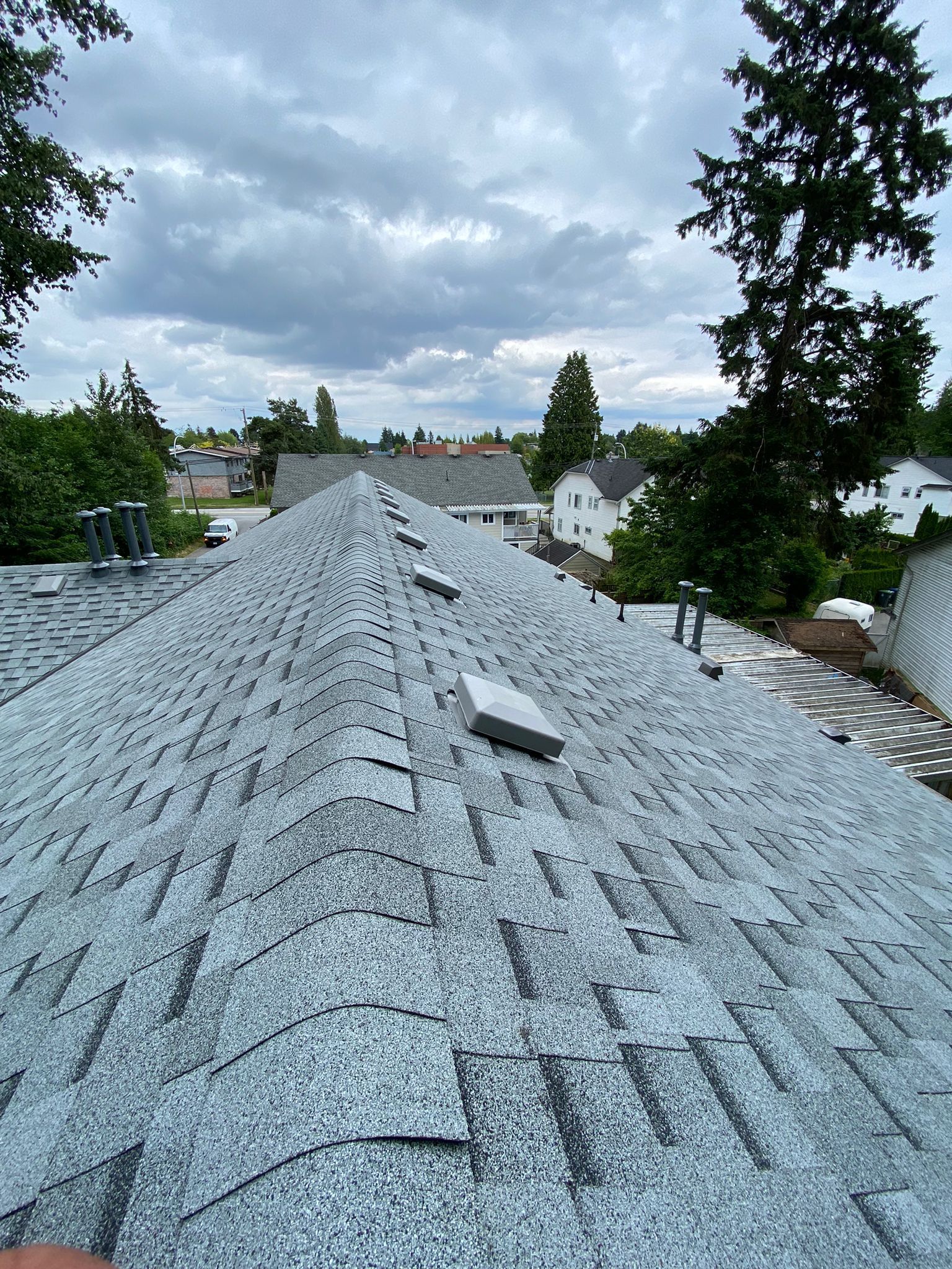 A roof with a lot of shingles on it and trees in the background.