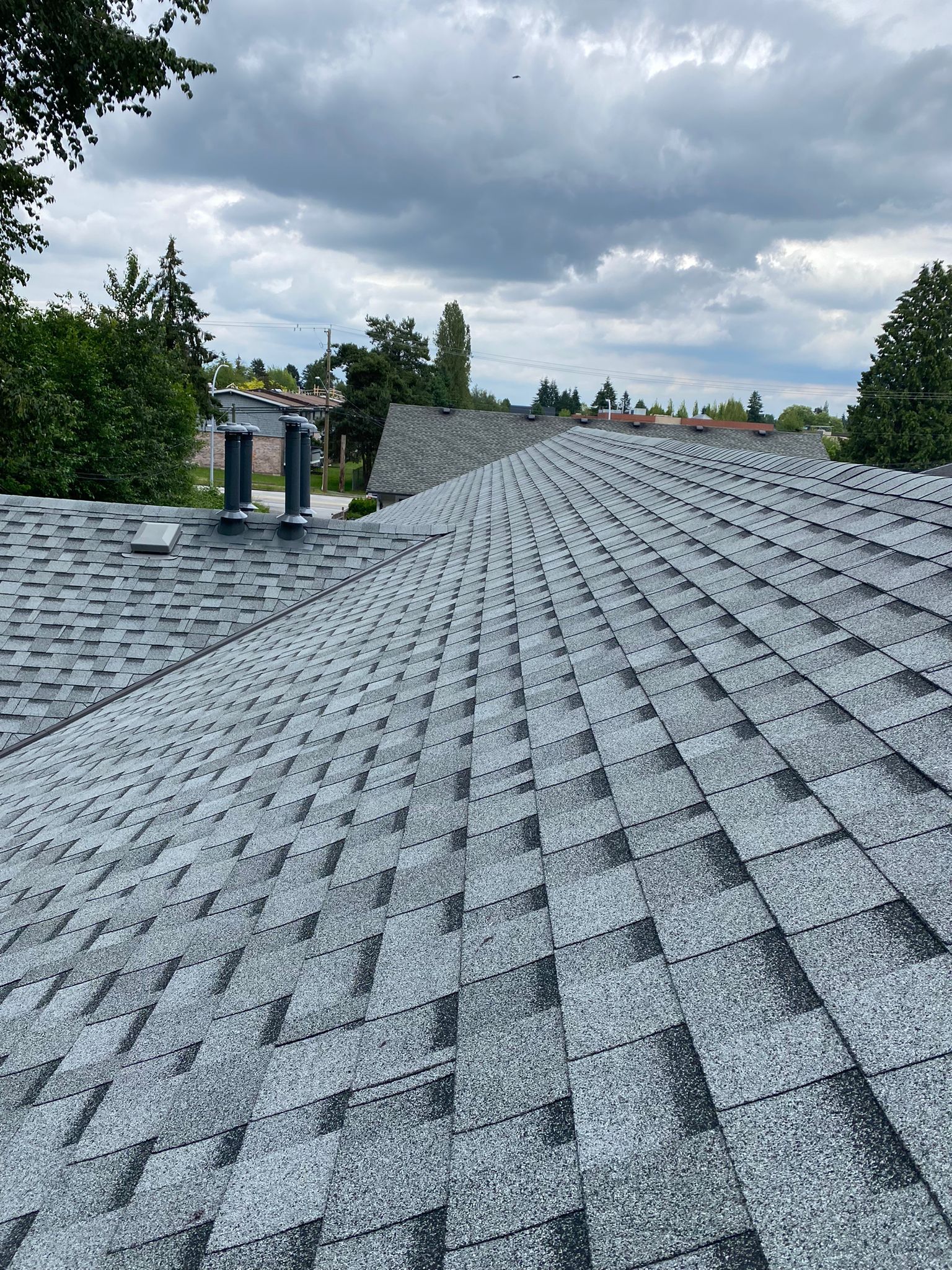 A roof with a lot of shingles on it and a cloudy sky in the background.