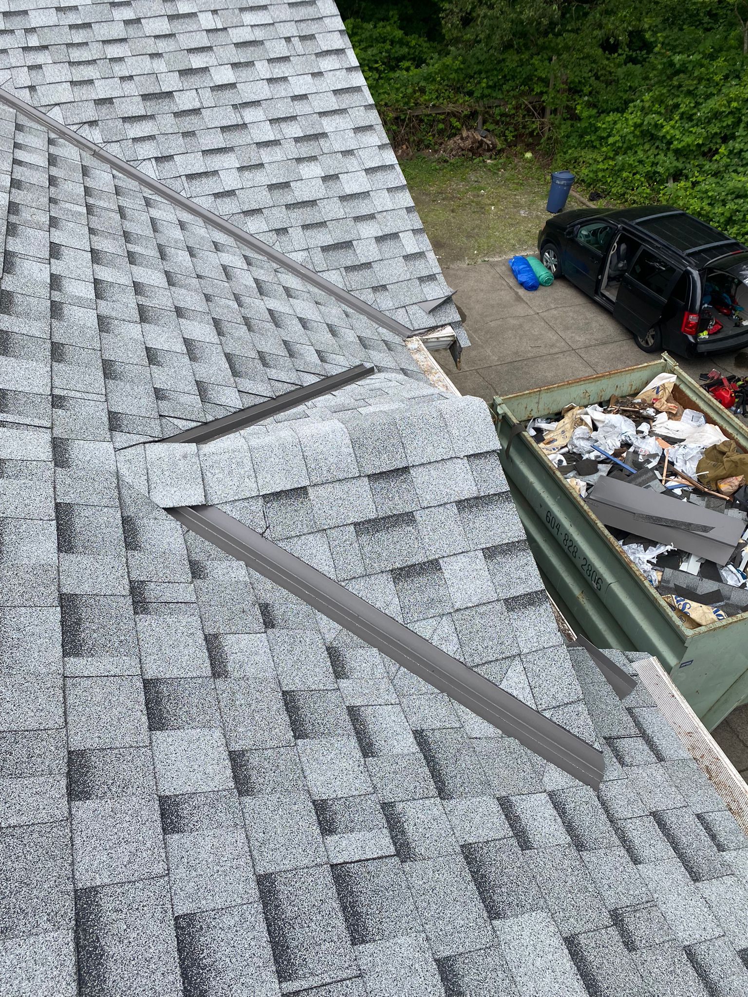An aerial view of a roof with shingles being installed.