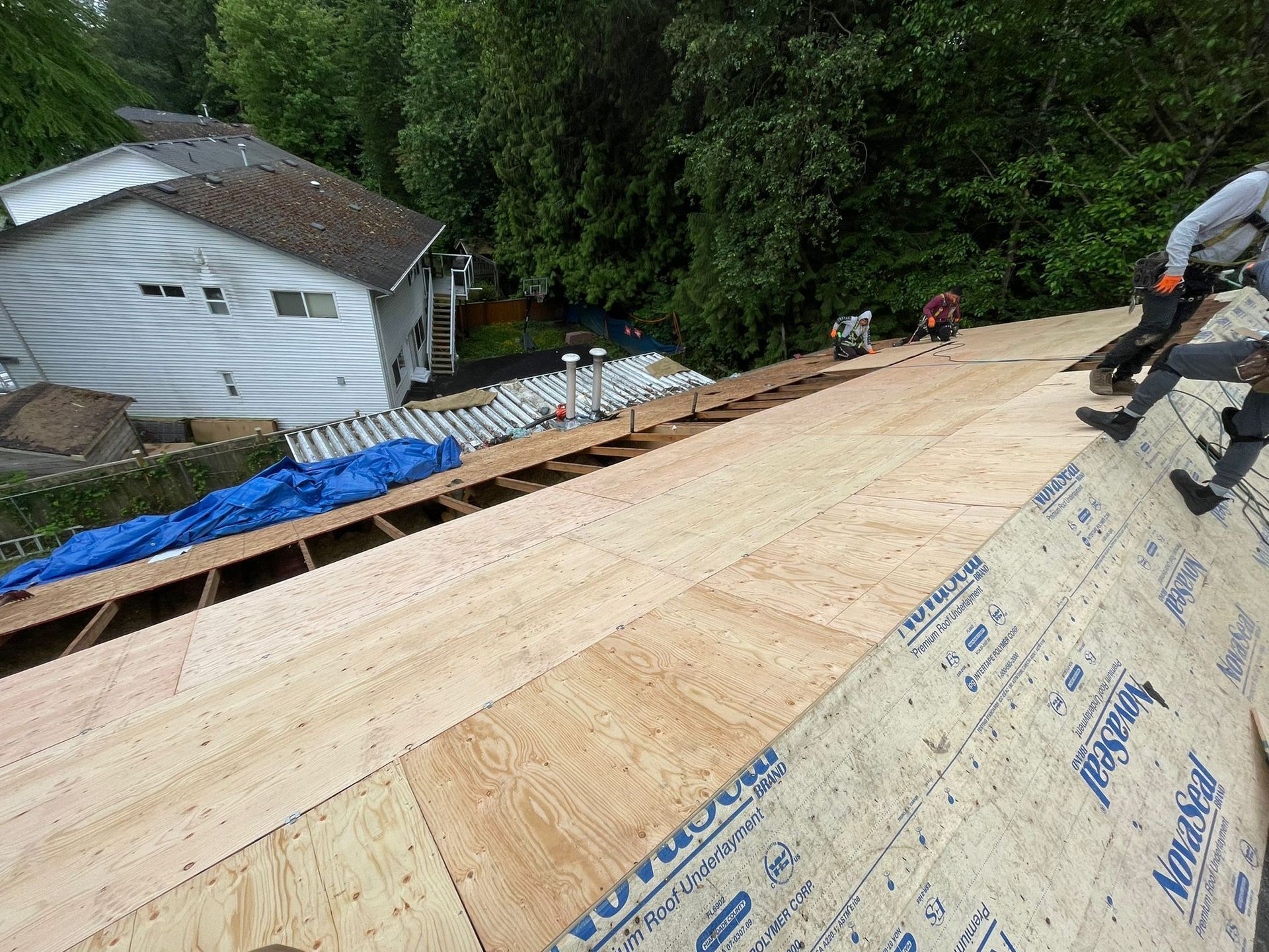 A group of people are working on the roof of a house.