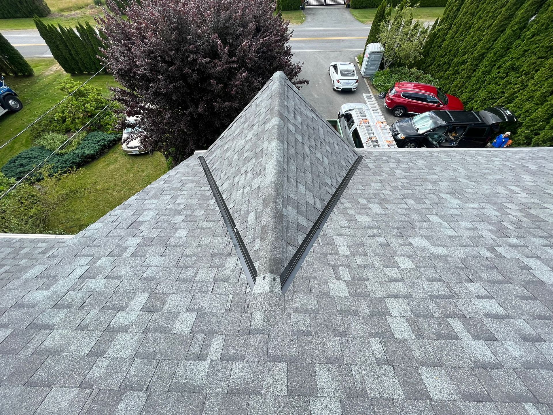 A high-angle view of a gray shingled roof featuring a prominent triangular dormer extending from the roofline.