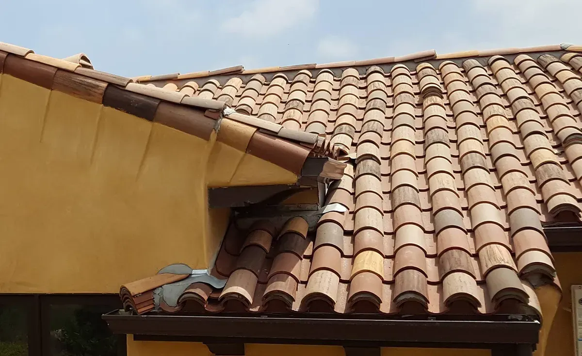 A roof with a vent on it and a building in the background.